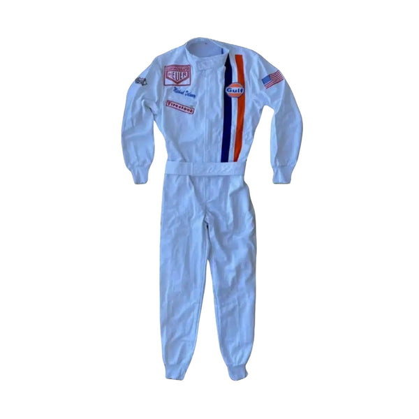Front view of Michael Delaney’s 1971 Le Mans racing suit worn by Steve McQueen, featuring off-white base, vertical Gulf racing stripes in blue and orange, and vintage patchwork detailing.