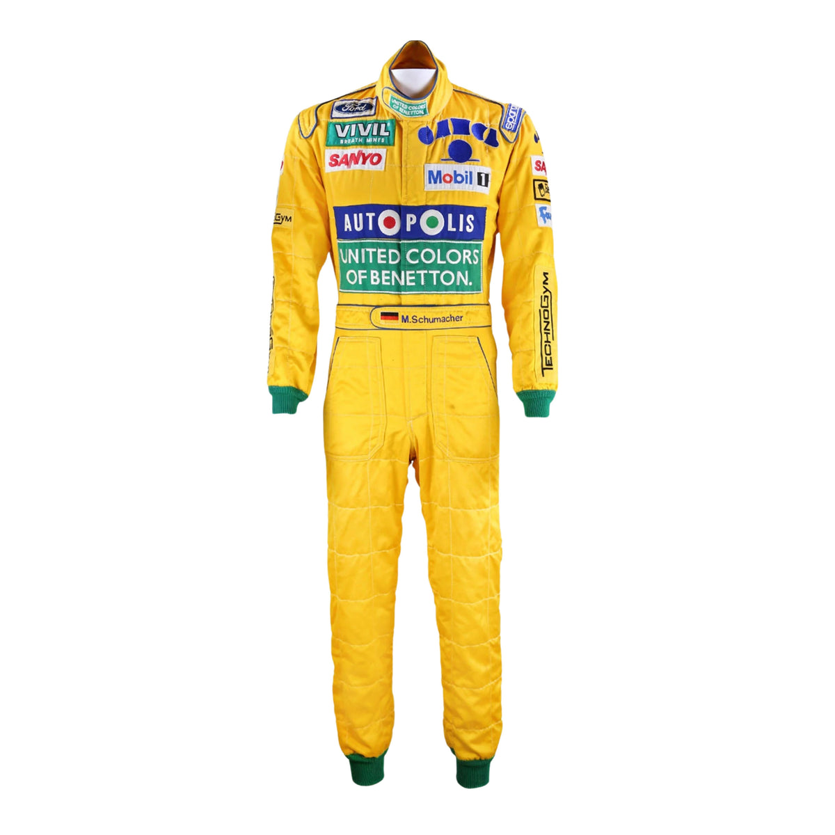 Front view of Michael Schumacher's 1992 F1 racing suit featuring deep green with yellow accents, signature Benetton sponsorship, and classic zip-front design. Main image